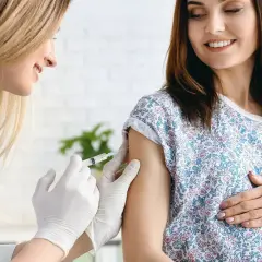 Ärztin verabreicht schwangerer Frau Impfung. Boostrix Polio schützt Mutter und Kind.