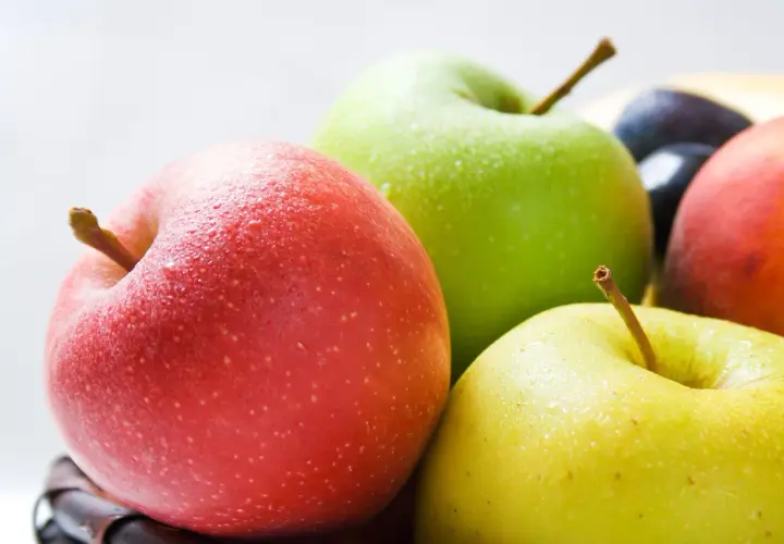 Frische Äpfel in Rot, Grün und Gelb, mit Wassertropfen bedeckt. Sie sind ein gesunder Snack und bieten gute Apfel Nährwerte.