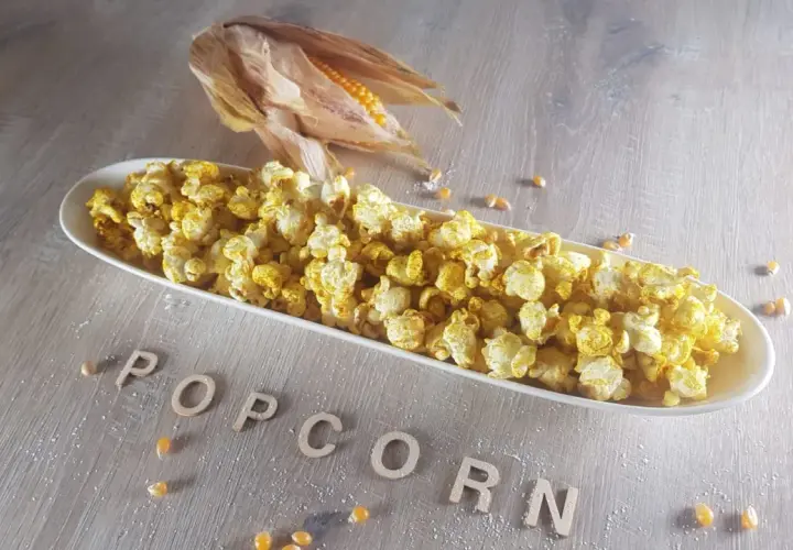 Leckeres Popcorn in einer Schale, daneben ein Maiskolben. Informiere dich über die Mais Nährwerte für einen gesunden Snack.